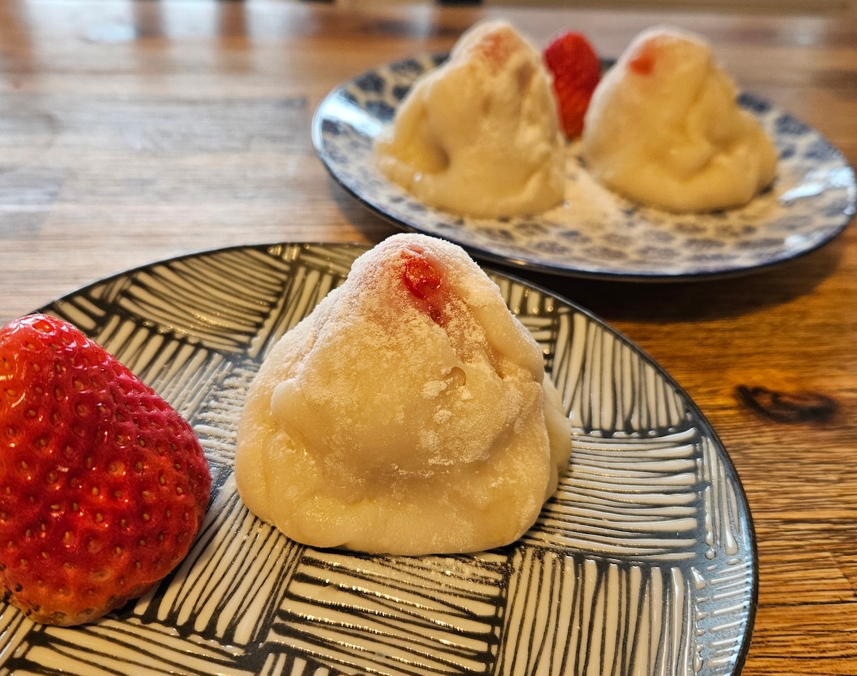 „Leuchtend rote Erdbeer-Daifuku, handgemachtes japanisches Wagashi auf einem weißen Teller – frühlingsfrisch und verlockend“